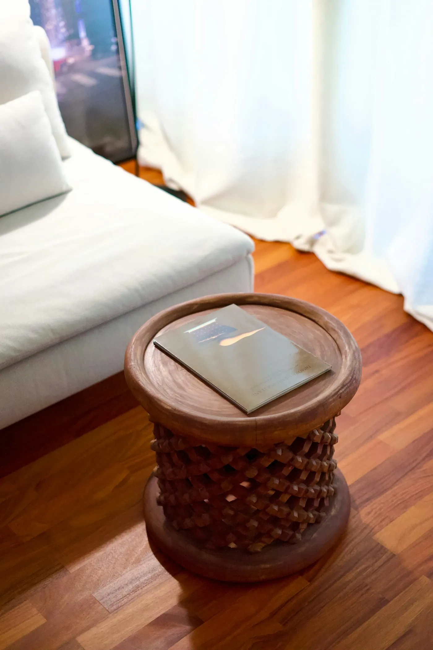 Tabouret sculpté au pied d'un canapé blanc